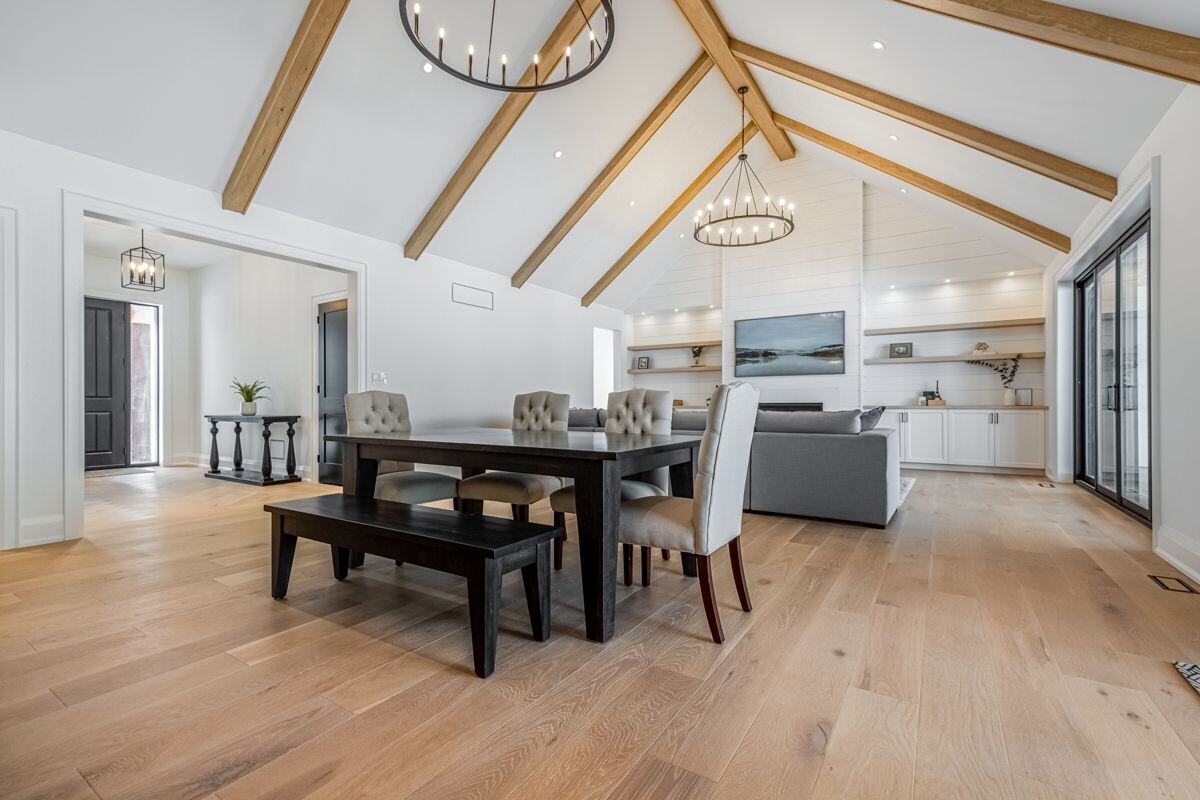 A bright, open-concept dining and living area with vaulted ceilings and exposed wooden beams in a modern Ontario home | Ever After Homes