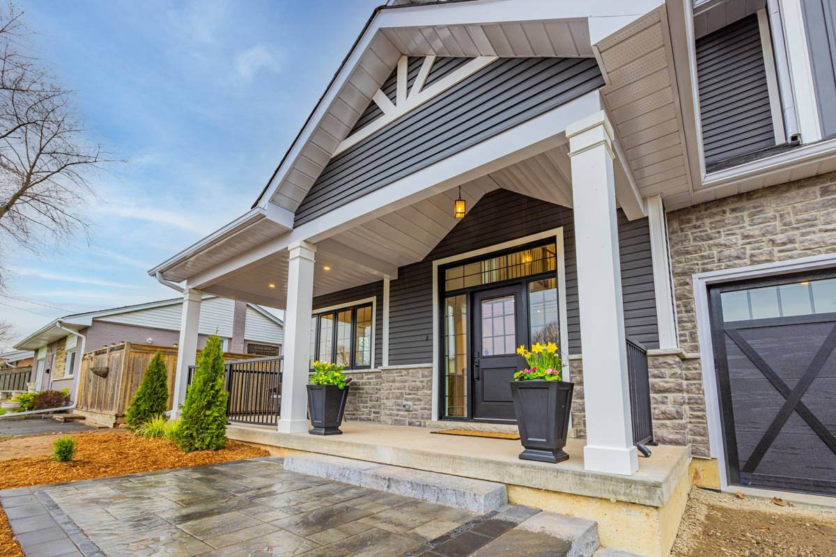The charming exterior of an Ontario home with a welcoming front porch, stone accents, and landscaped walkway | Ever After Homes.